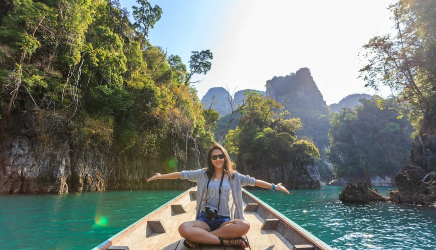 Asian woman relishing a serene boat journey through the lush karst landscape of Thailand's Khlong Sok.